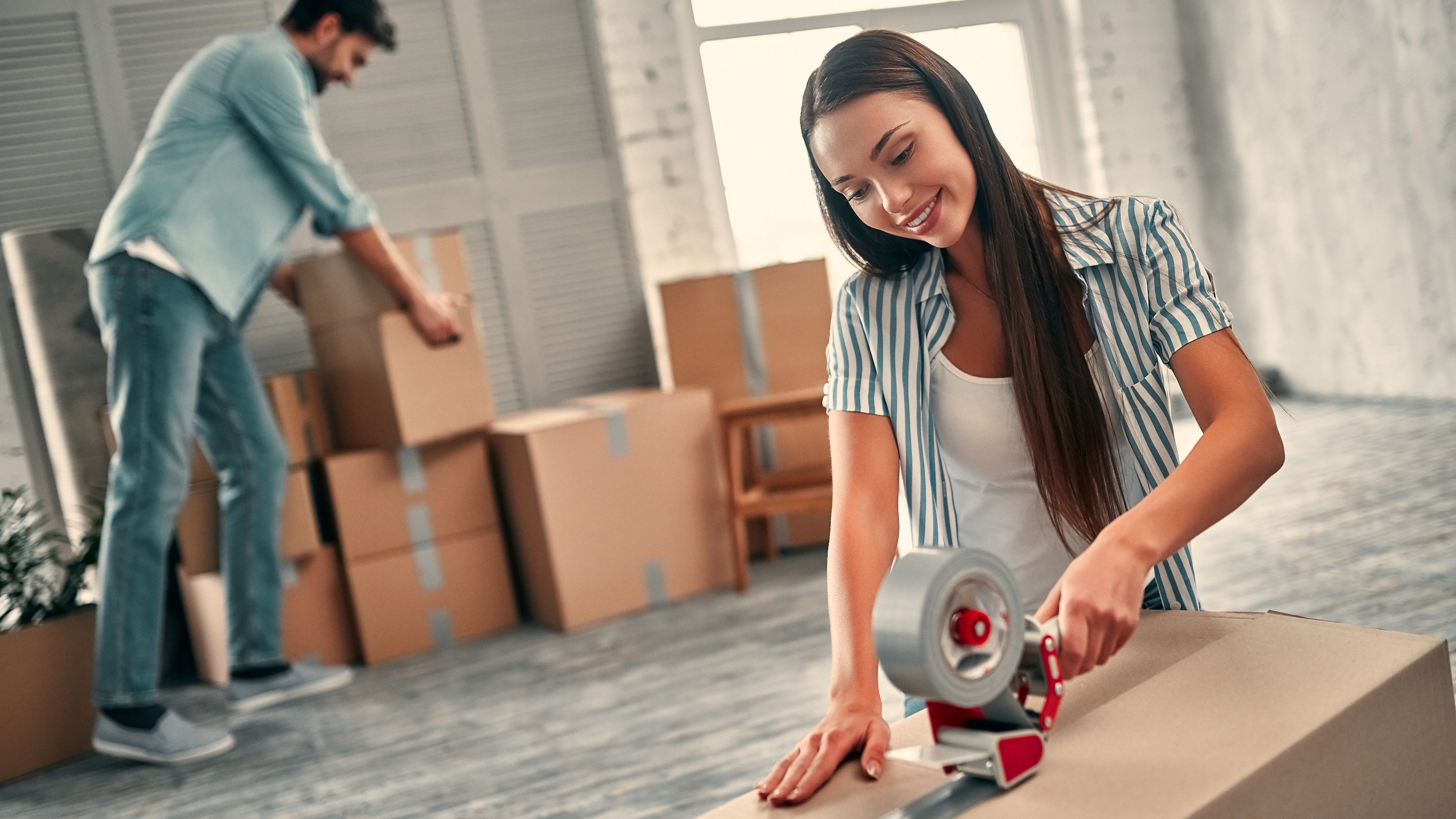 Couple on moving day. Attractive young woman and handsome bearded man with cardboard moving boxes are happy to move into new home.