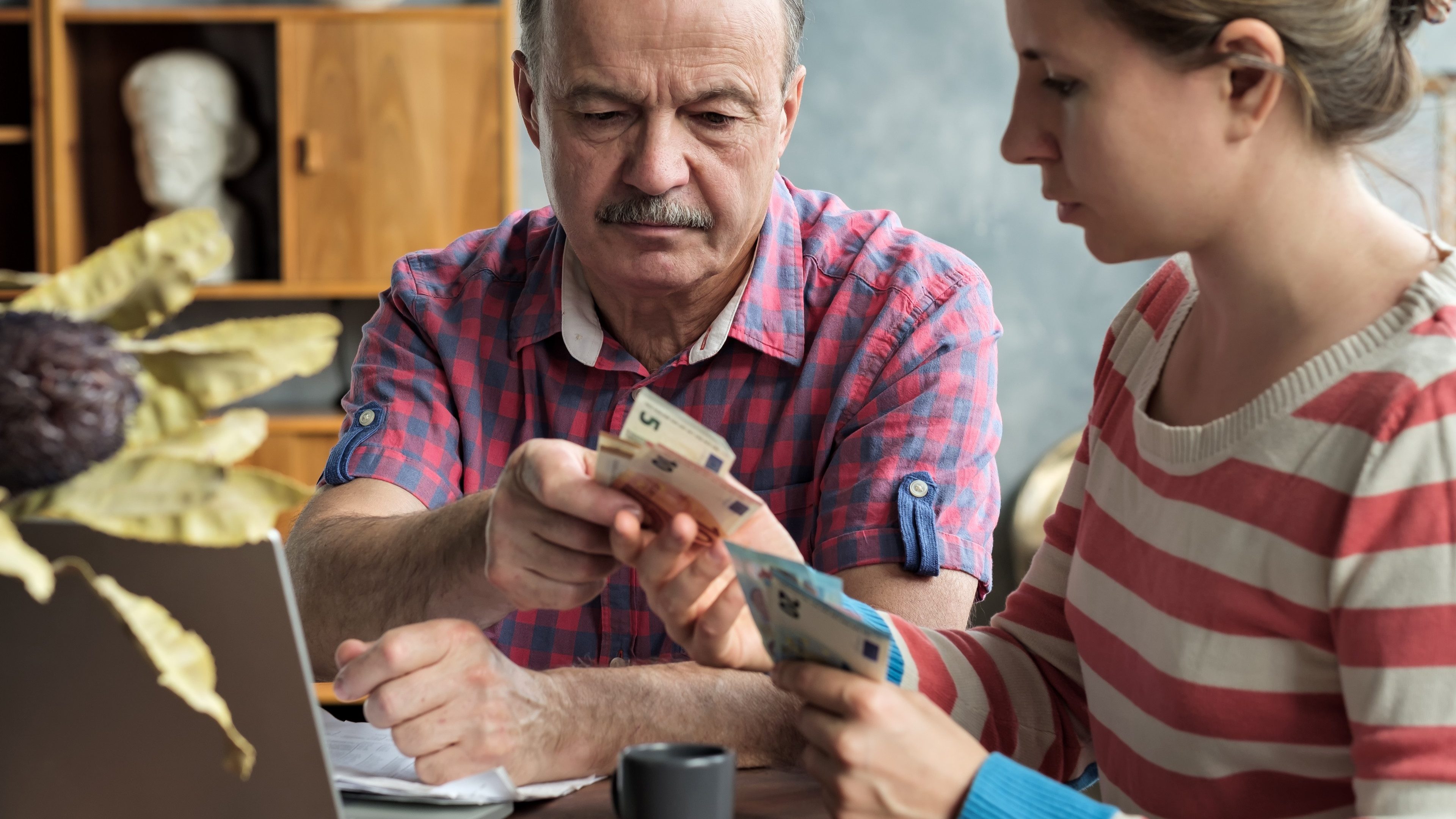 Olderly Spanish man gives his daughter money for a mortgage or student loan. Helping children while retired.