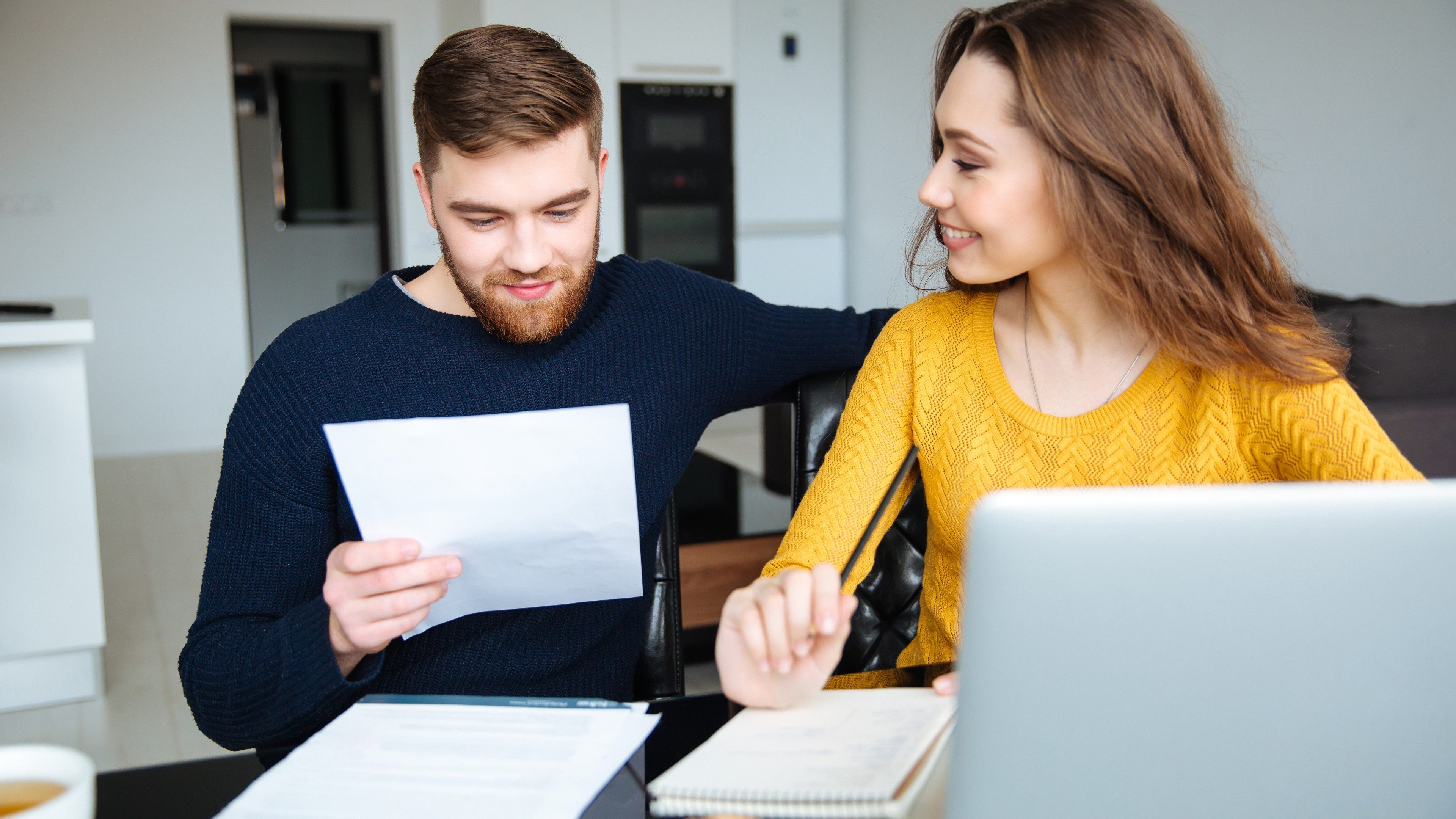 Happy young couple calculating bills at home
