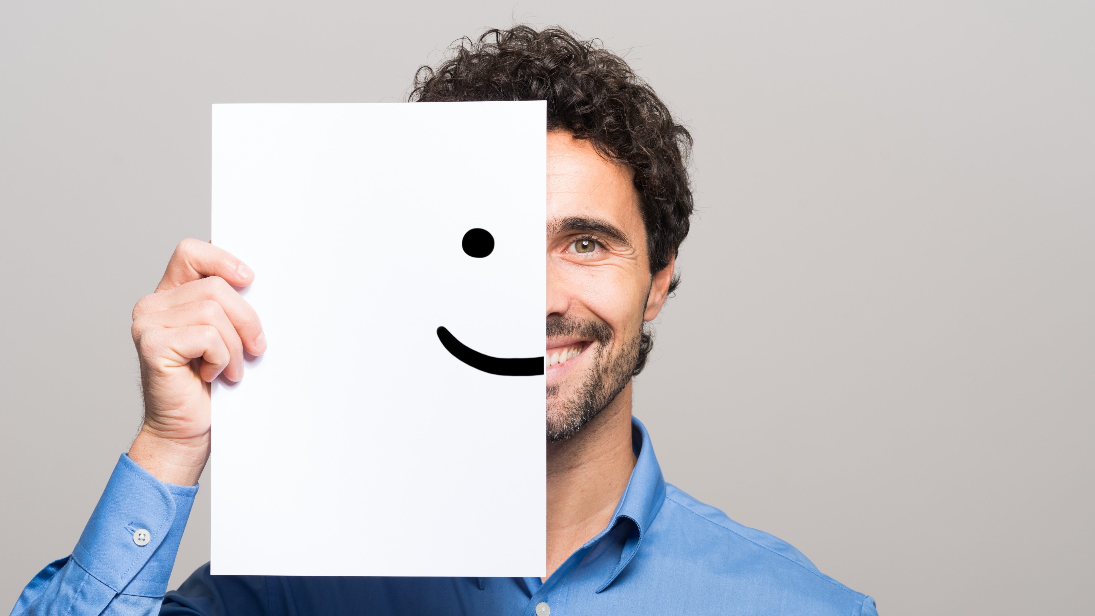 Happy man covering half his face with a smiling emoticon