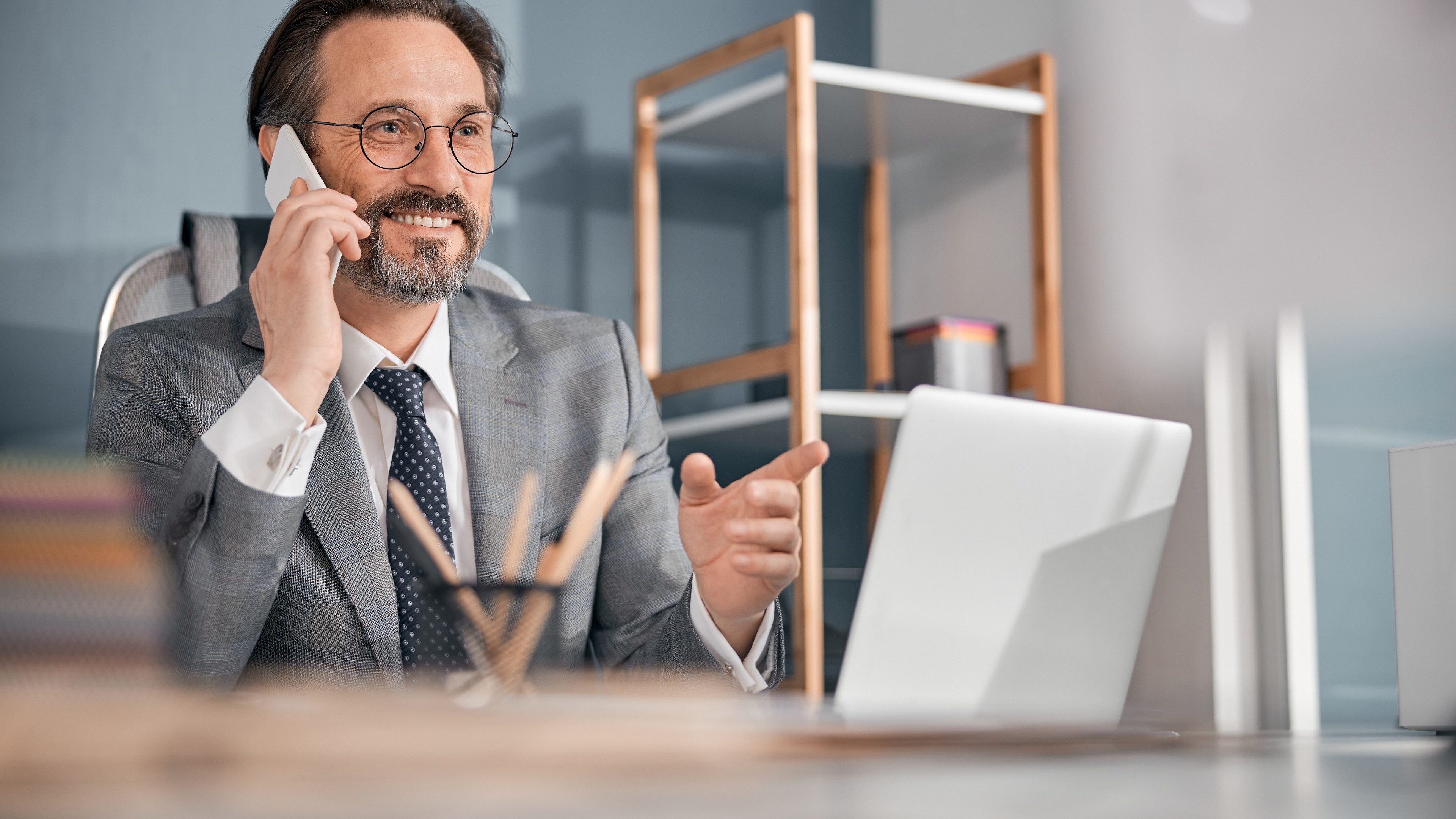 Handsome bearded man having phone conversation and smiling while sitting at the table in office