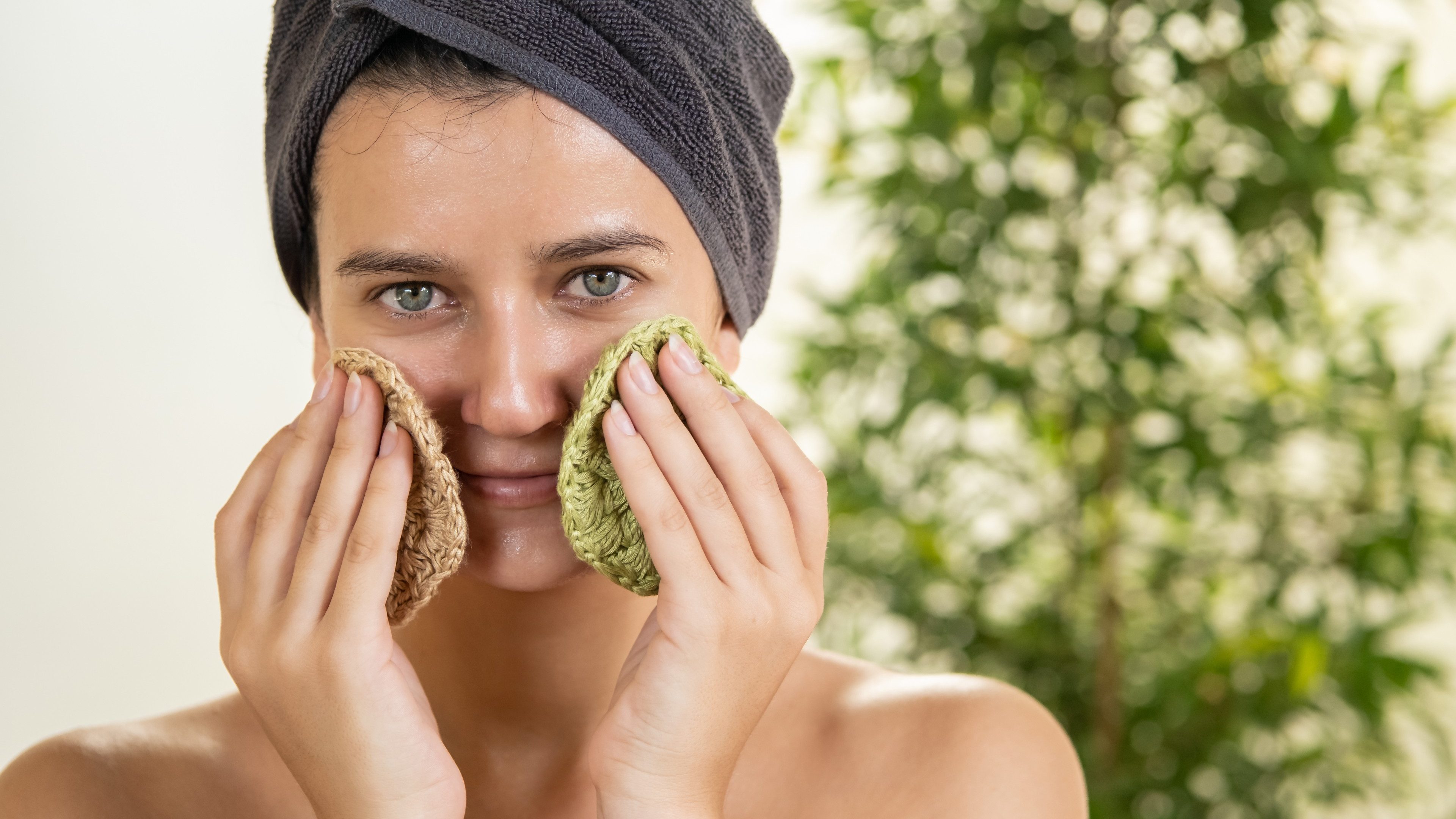 Young woman washing her face with reusable crocheted pads in bathroom. DIY washable knitted makeup remover cloth. Eco-friendly cosmetic products. Zero waste and sustainable plastic free lifestyle