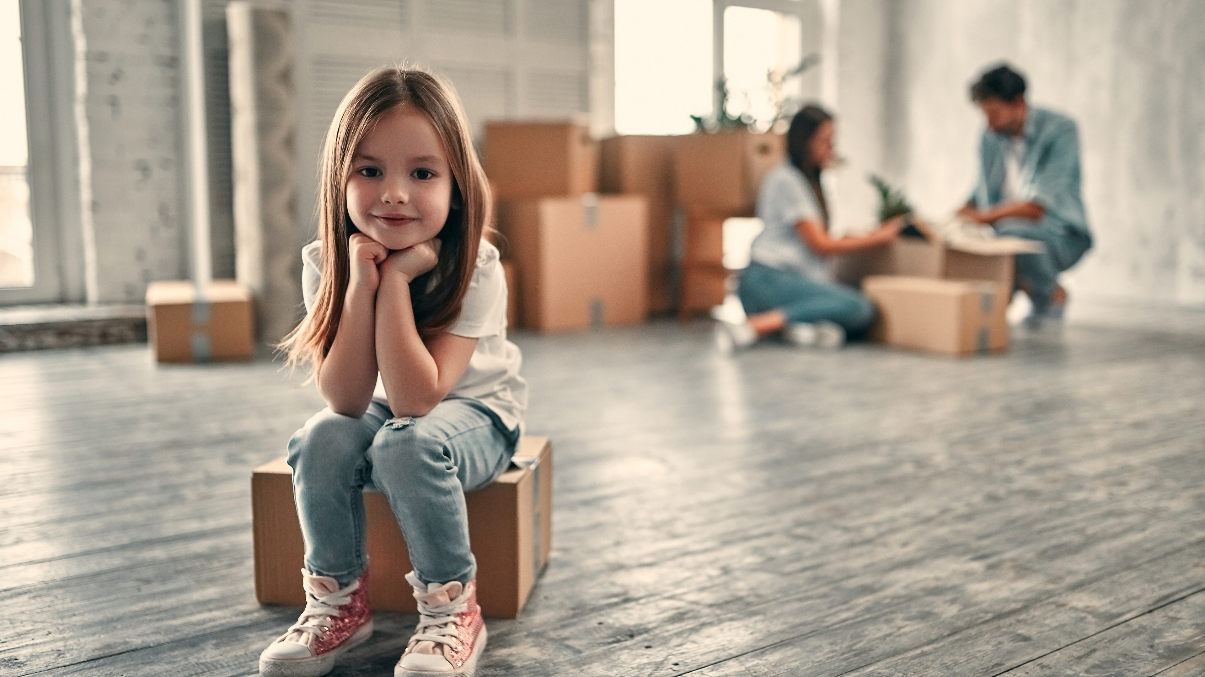 Family on moving day. Attractive young woman and handsome bearded man with their cute little daughter are happy to move into new home.