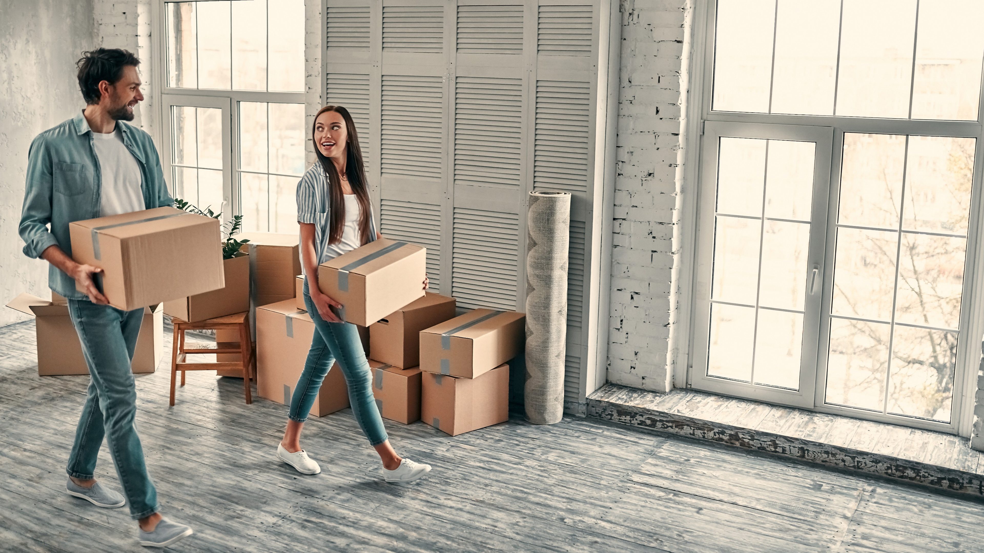 Couple on moving day. Attractive young woman and handsome bearded man with cardboard moving boxes are happy to move into new home.