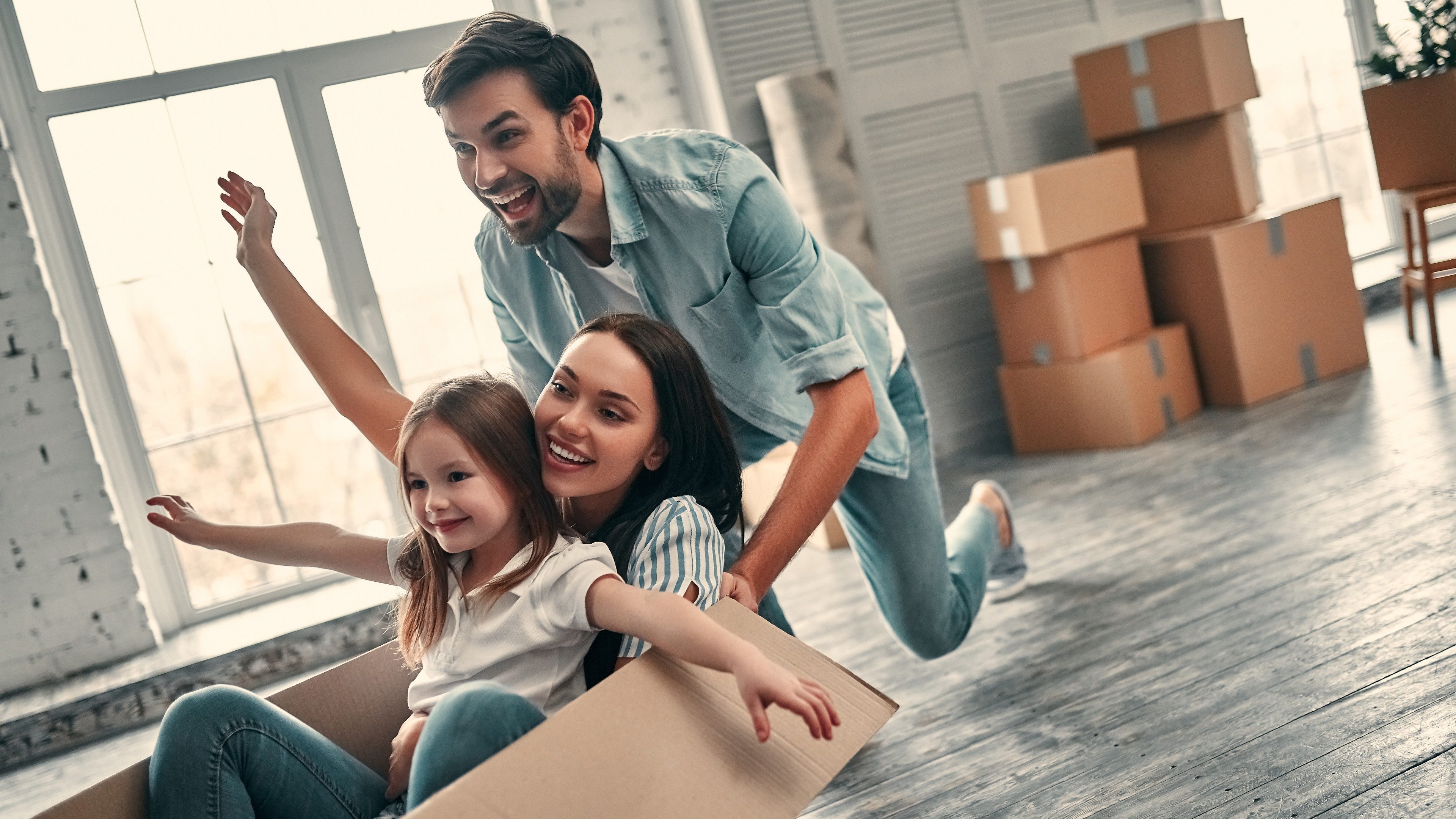 Family on moving day. Attractive young woman and handsome bearded man with their cute little daughter are happy to move into new home.