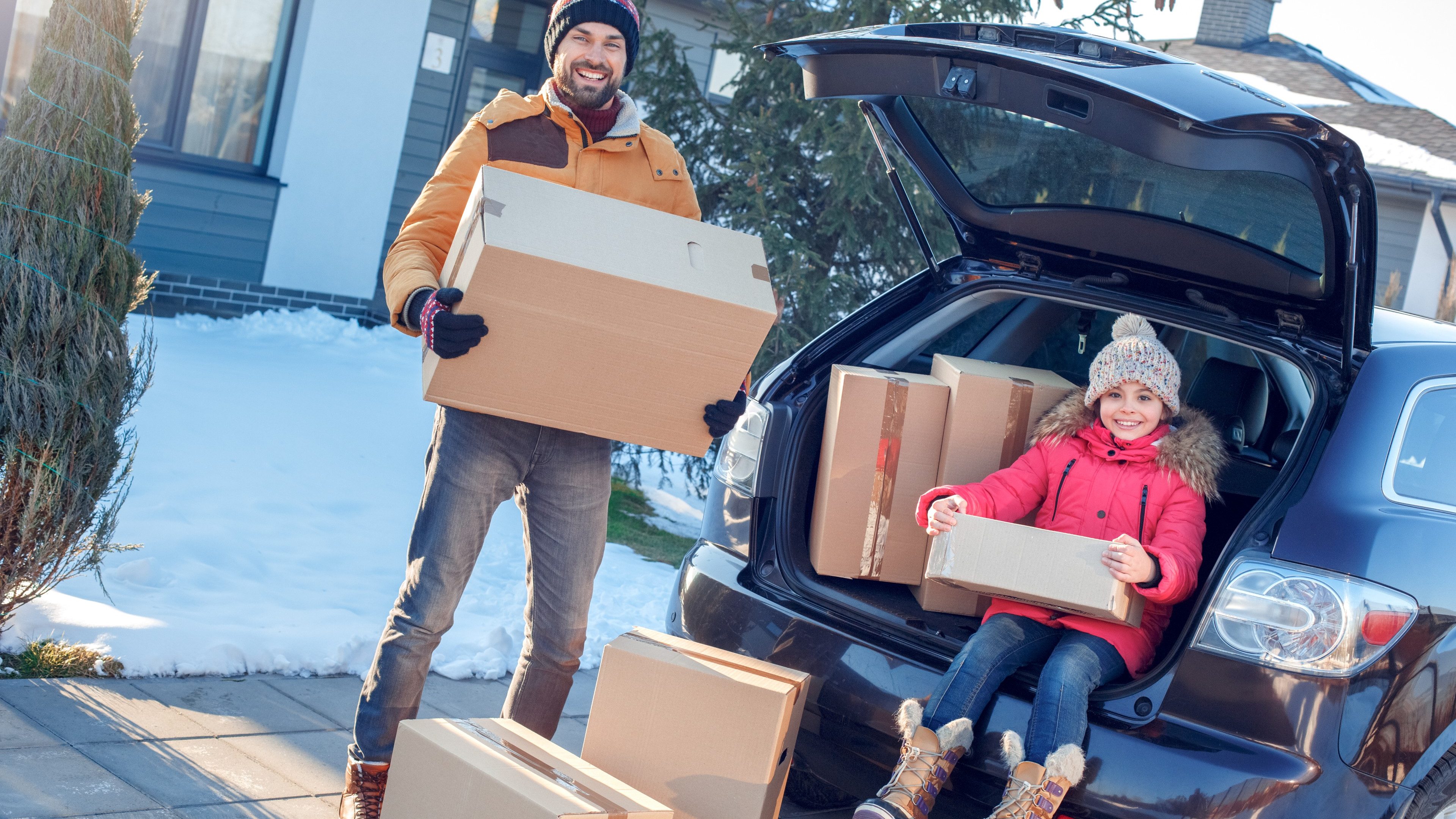 Fsther and daughter moving to new apartment together during winter standing outdoors near car taking boxes from trunk looking camera smiling excited