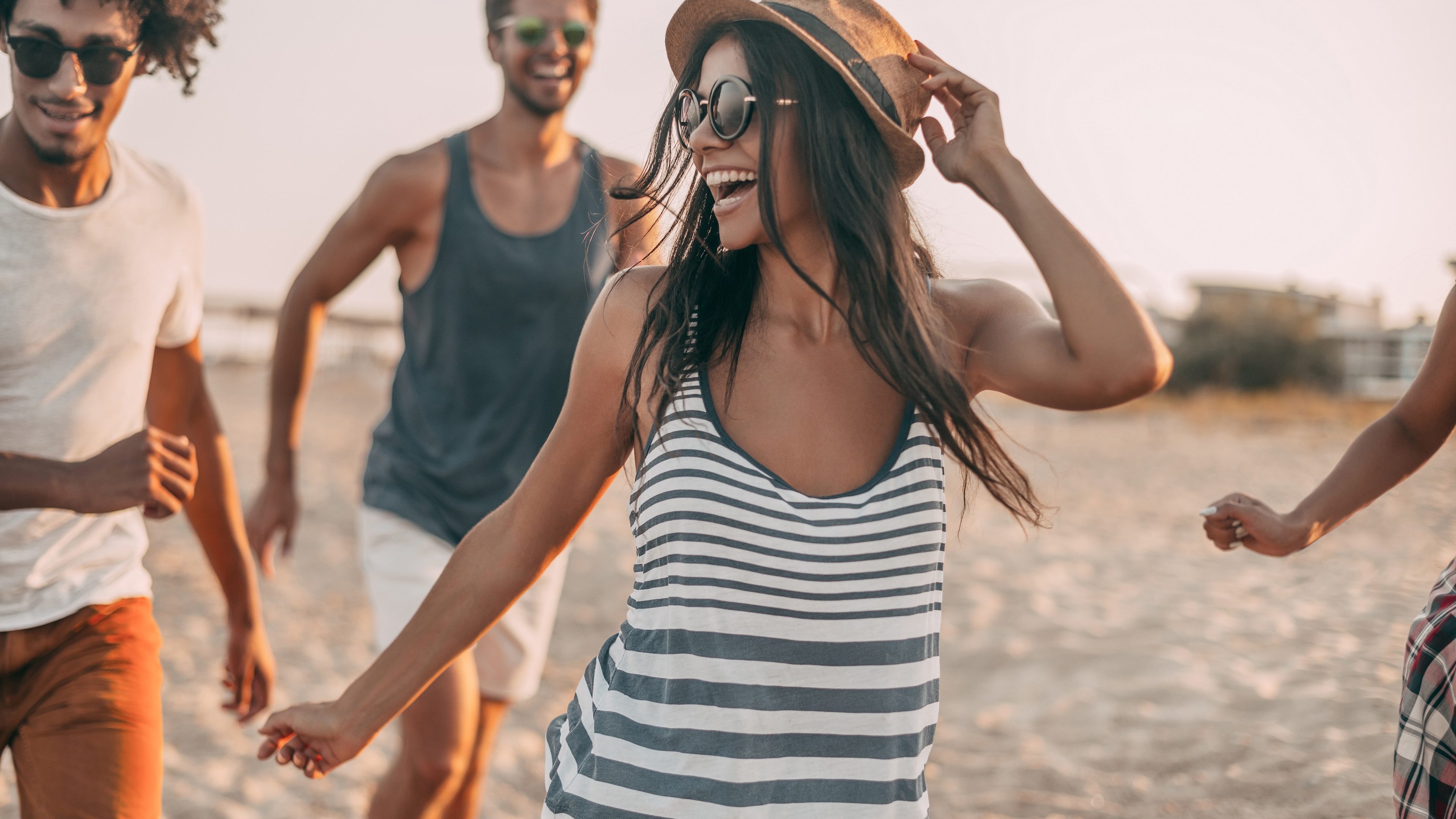 Enjoying youth and freedom. Group of young cheerful people running along the beach and looking happy