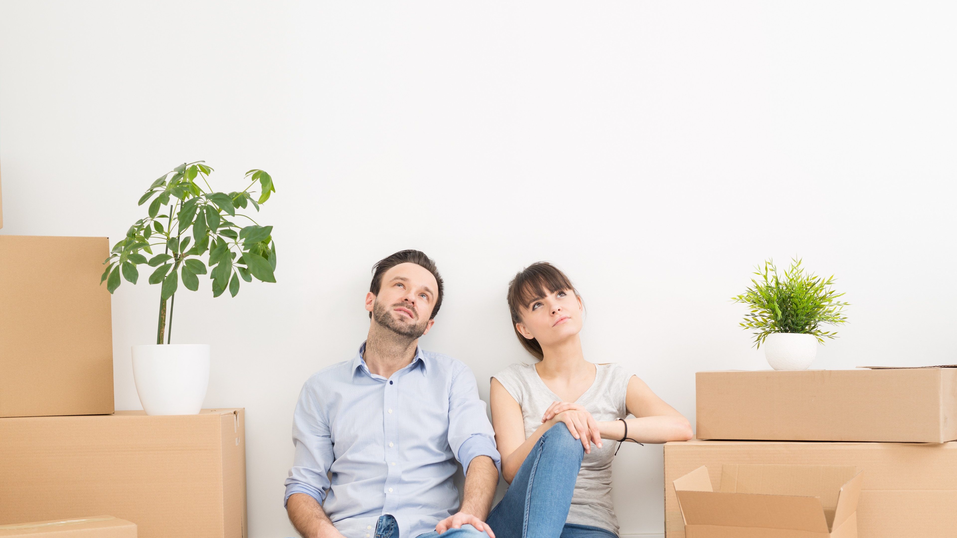 A young couple sitting on the floor and looking up. Dream and enjoy your new home.