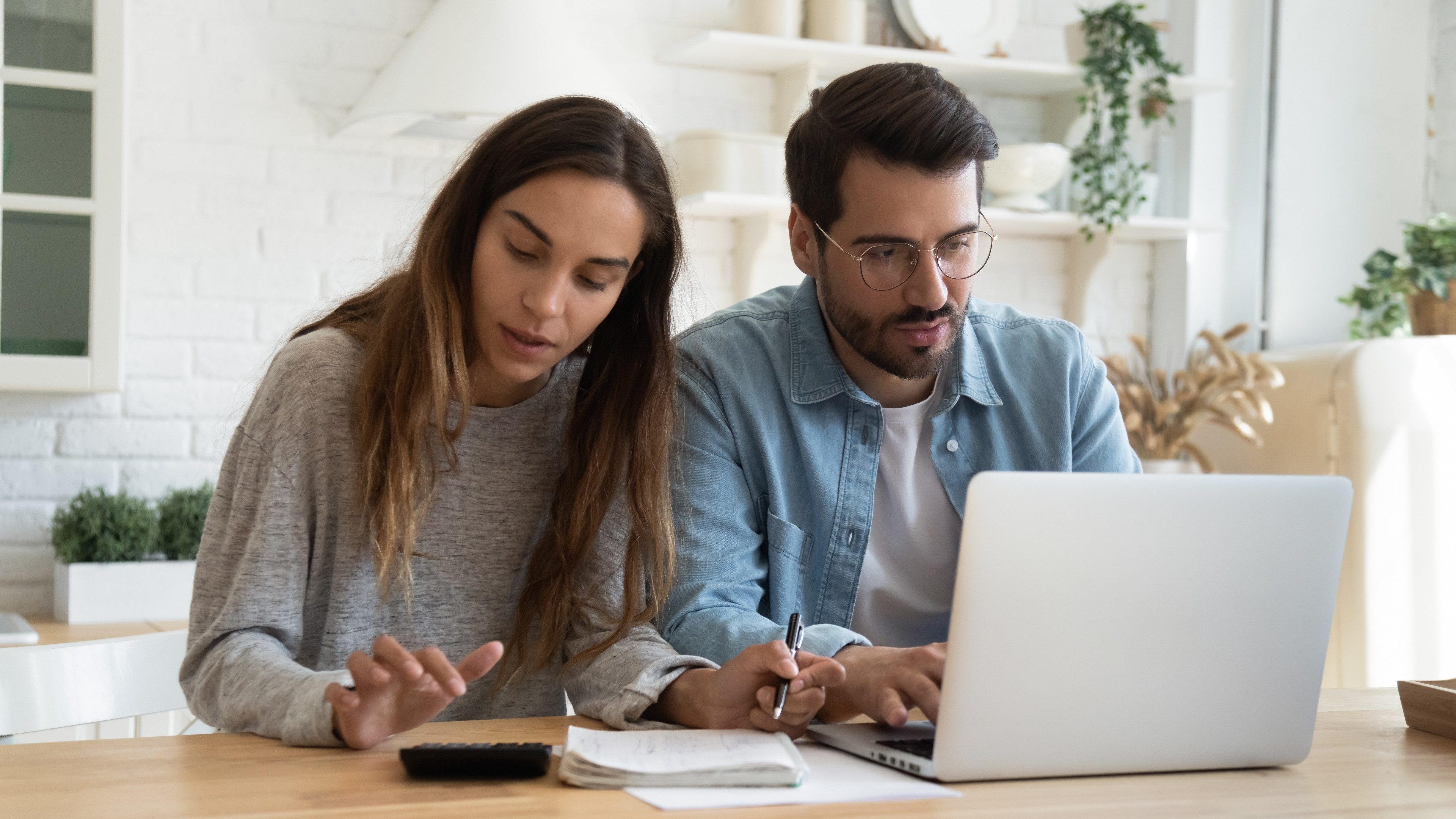 Serious man and woman calculating bills, using calculator and laptop, online banking services, family discussing and planning budget, focused wife and husband checking finances together