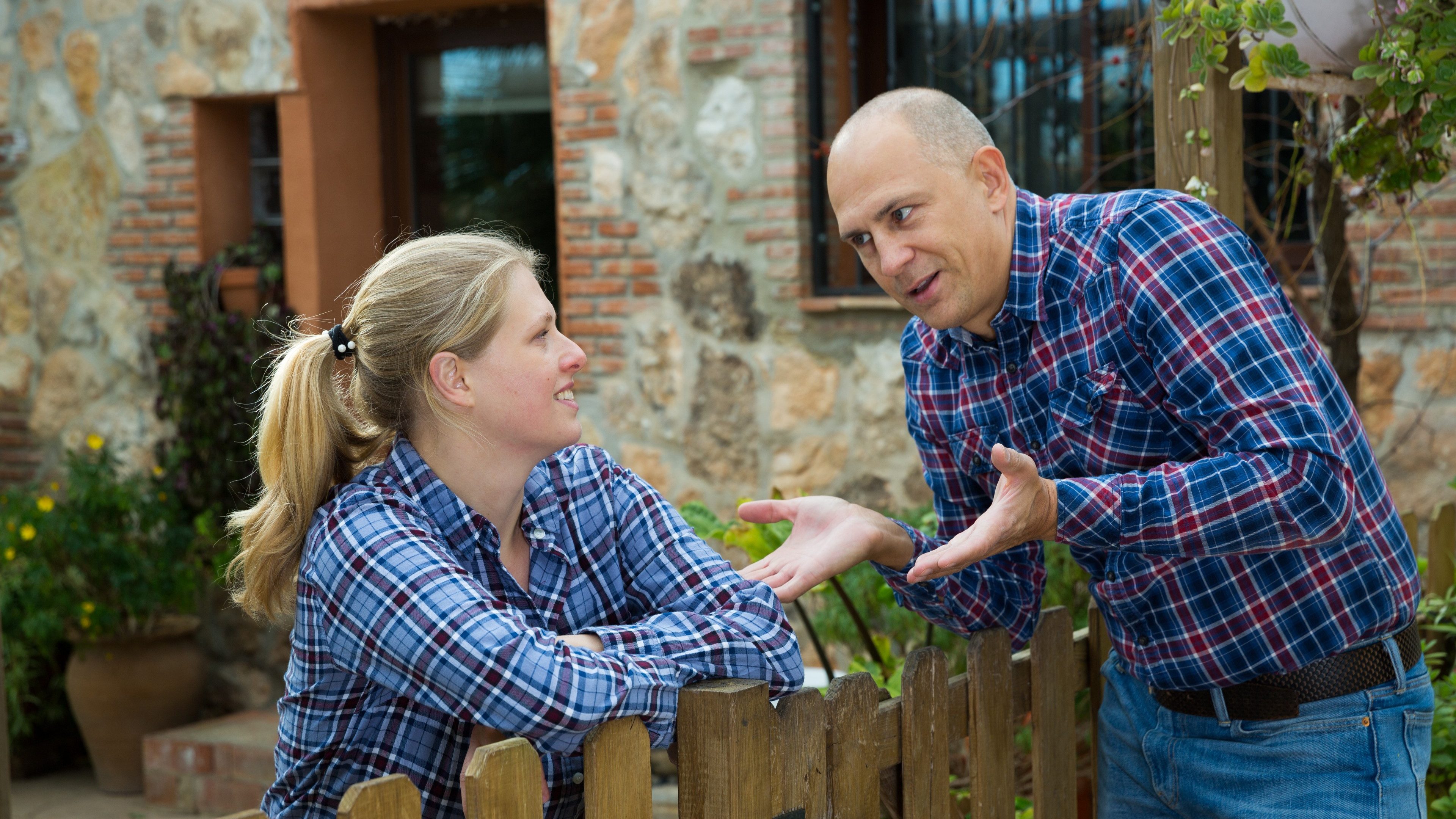 Man and woman communicate in a friendly way on the border of their farms. High quality pot