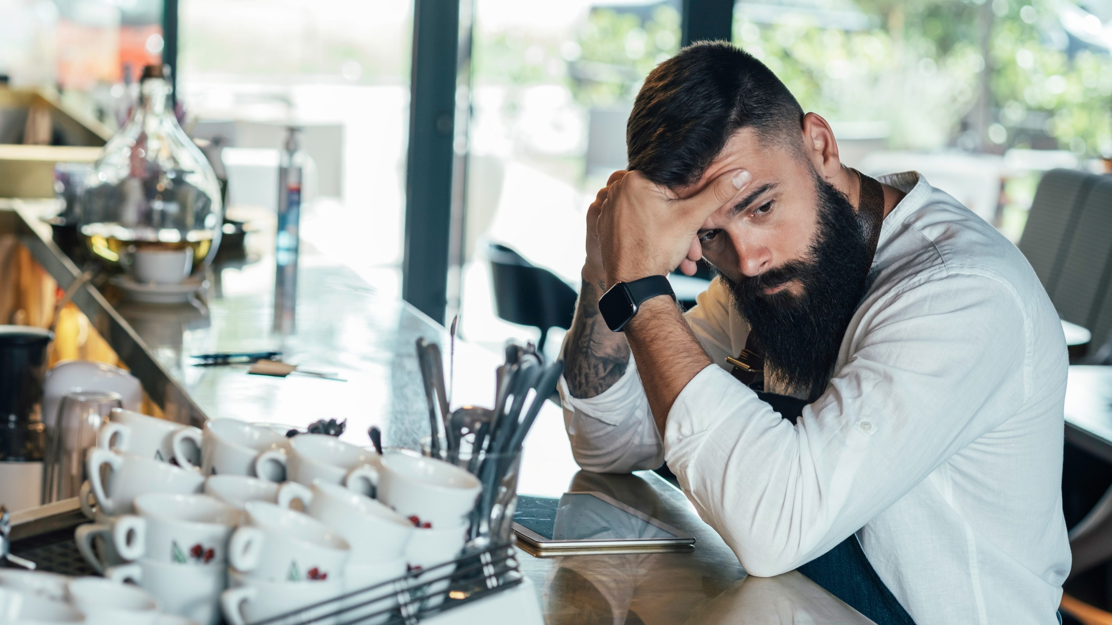 Worried Barista Using Digital Tablet in a Cafe.