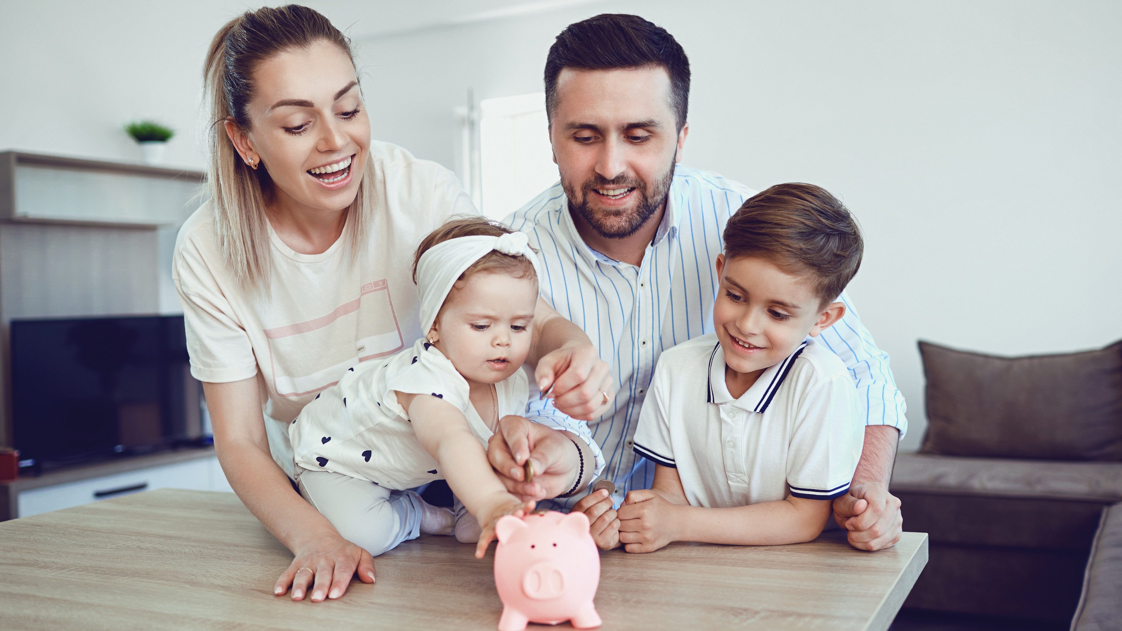 A smiling family saves money with a piggy bank. 