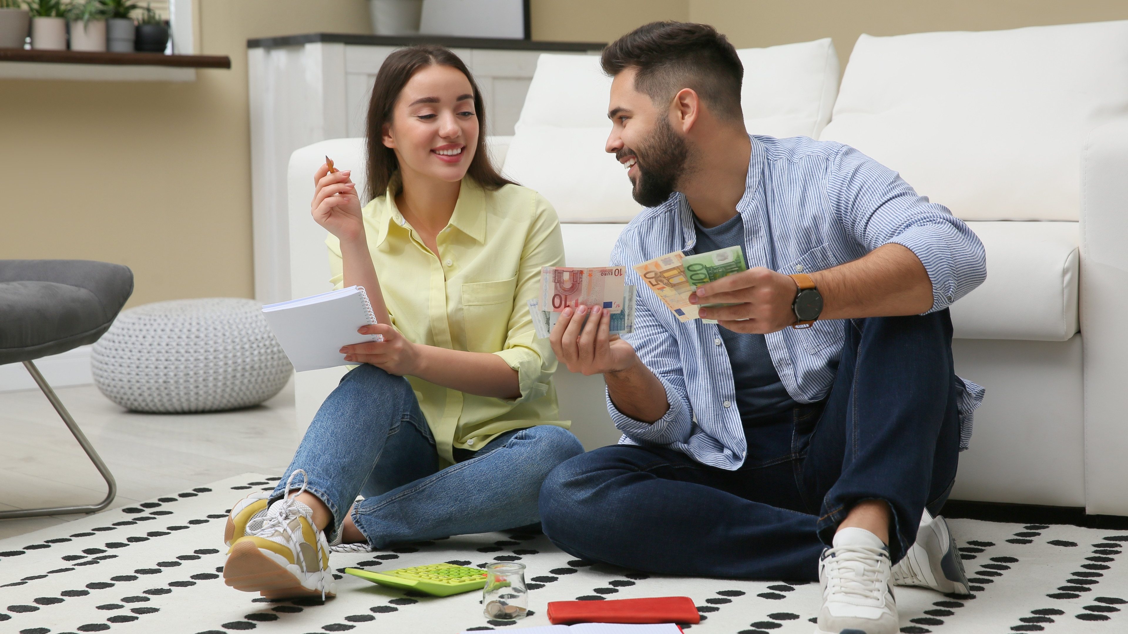 Happy couple counting money on floor at home