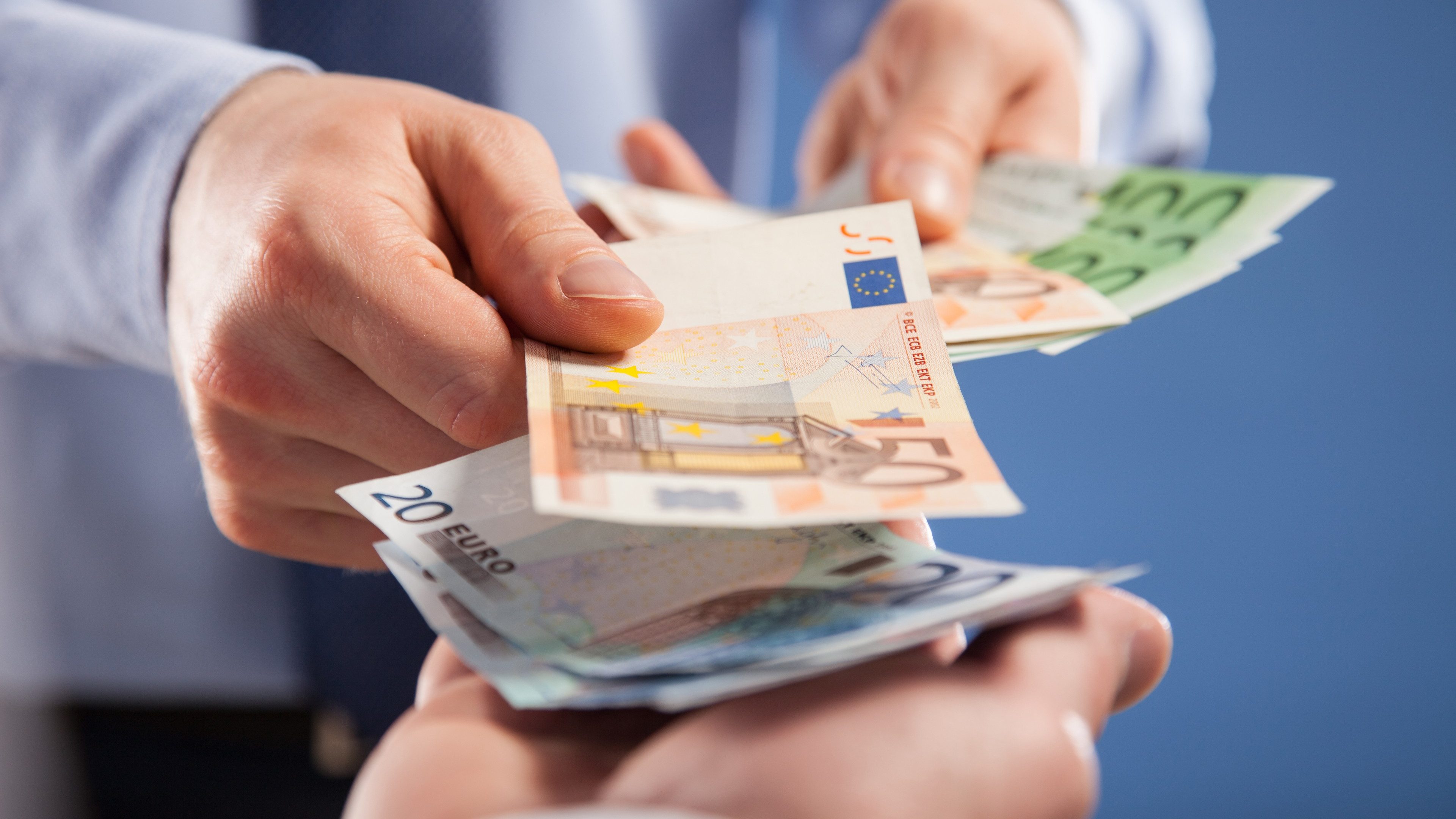 Businessman's hands exchanging euro on blue background, closeup shot