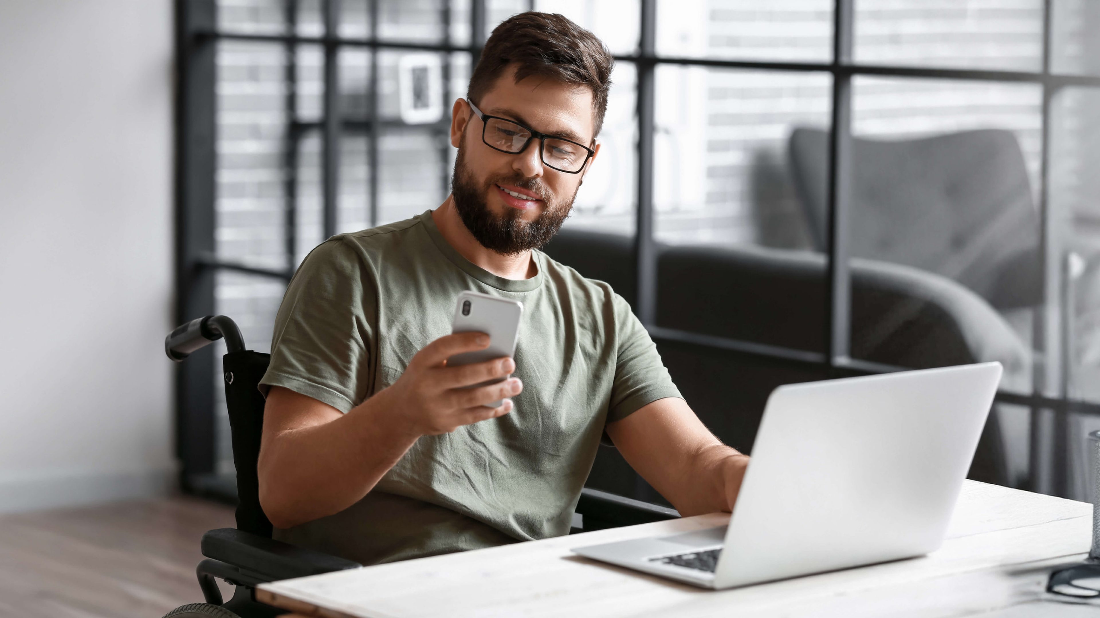 Vozičkár pracuje na počítači a mobilnom telefóne